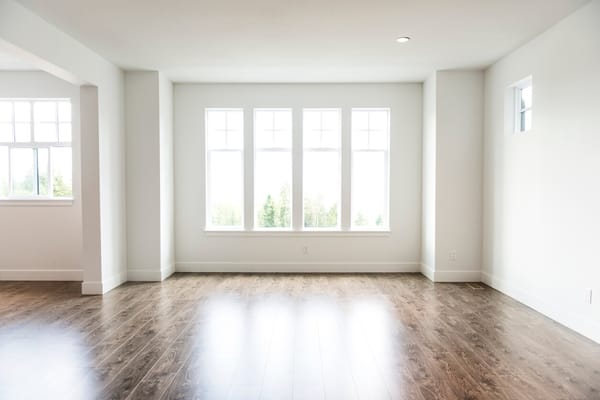 Empty rental living room with bare wood floors and tall windows after moving out
