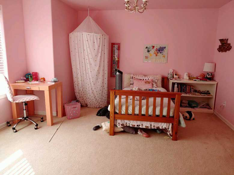 Messy girl's bedroom with pink walls, a craft table, bed, and castle tent before professional cleaning and organization in Bellevue.