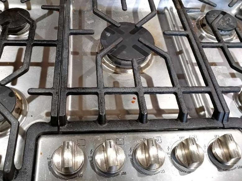 Greasy and dirty Bosch stainless steel 5-burner gas stove with visible food splatter and a Dacor downdraft hood before professional kitchen cleaning in Bellevue.