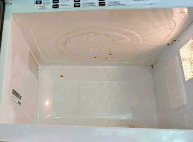 Dirty microwave interior with visible splashes, dried sauces, and food residue before professional deep cleaning in Bellevue.