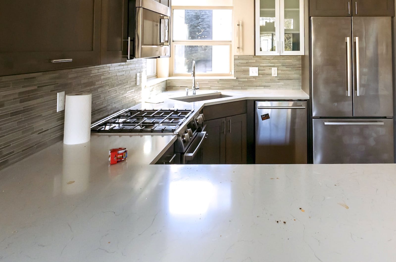 Before image of a Ballard Seattle townhouse kitchen showing messy engineered stone countertops, crumbs, and items left behind before professional cleaning.