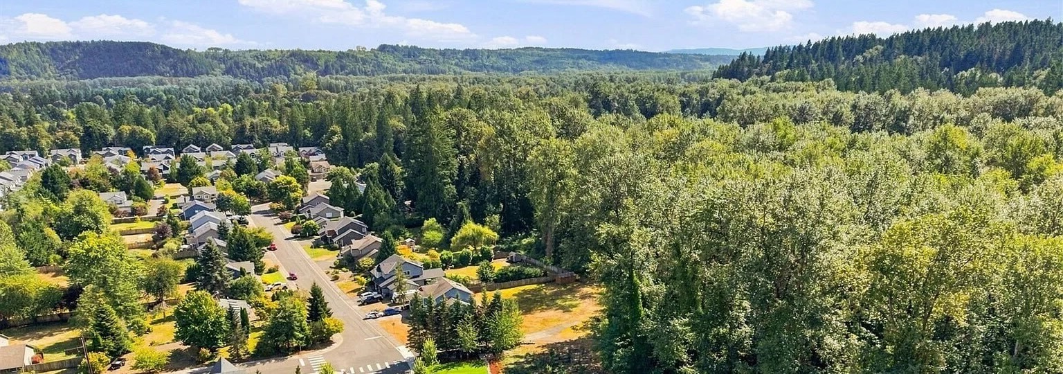 Aerial view of homes beside a wide stretch of forest in the Snoqualmie Valley, with wooded hills beyond