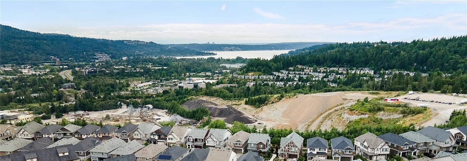 Aerial view of Issaquah hillside homes and forested valley, with Lake Sammamish in the distance