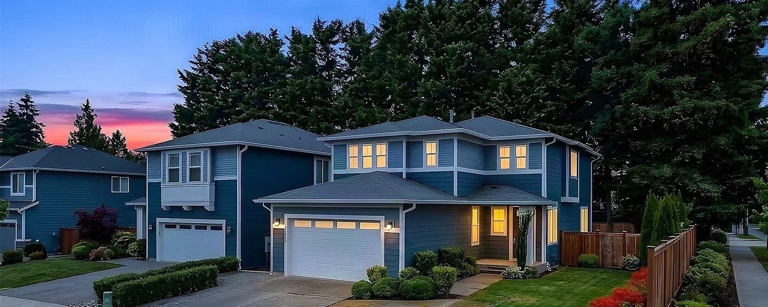 Two-story family homes with lit windows on a quiet Kent street at dusk