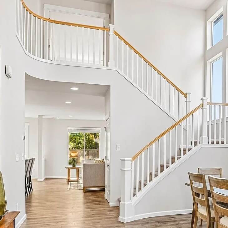 Bright two-story foyer with a curved staircase, white railings and wood floors