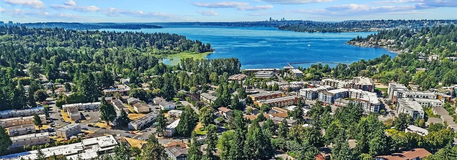 Aerial view of Kirkland homes and apartments among evergreen trees, with Lake Washington beyond