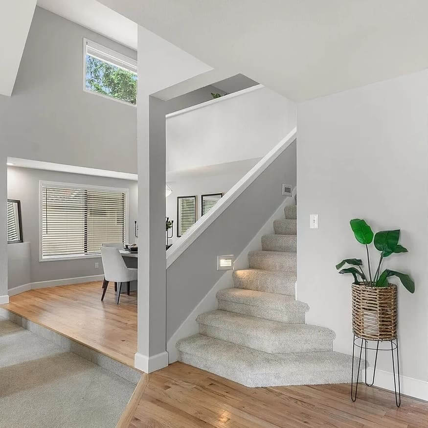 Bright split-level entry with carpeted stairs, hardwood floors and a dining area beyond