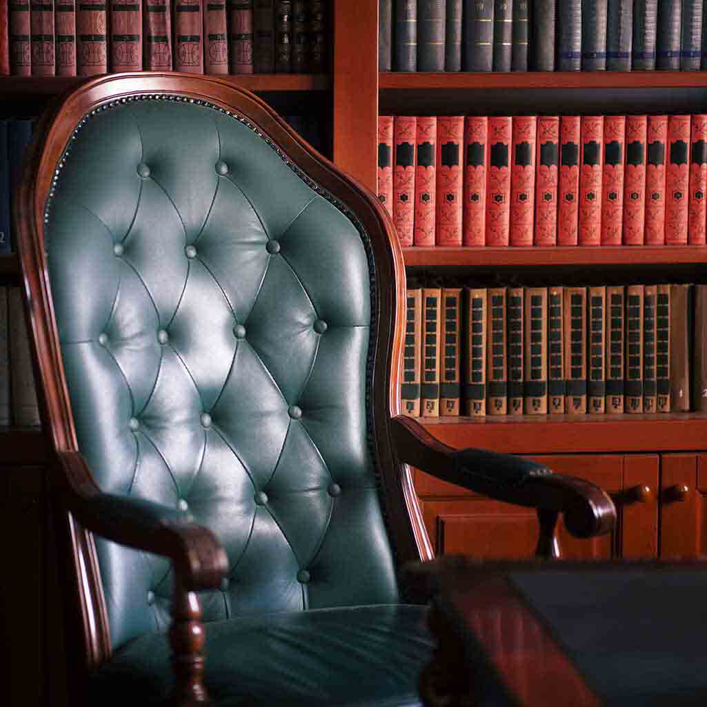 Clean law office interior in Seattle with green leather chair and book-lined shelves prepared for professional use
