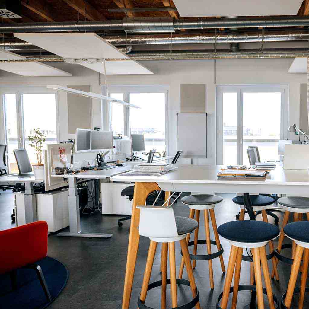 Collaborative nonprofit office workspace with desks, laptops, and shared meeting areas in a clean professional environment