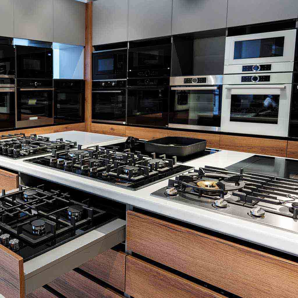A modern appliance showroom with clean stainless steel ovens, cooktops, and glass display surfaces, featuring polished floors and organized product displays before business hours in Seattle