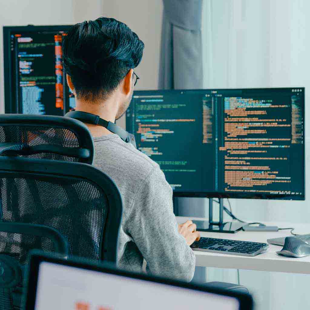Web development office with multiple computer monitors, organized desks, and clean workstations in a modern technology workspace