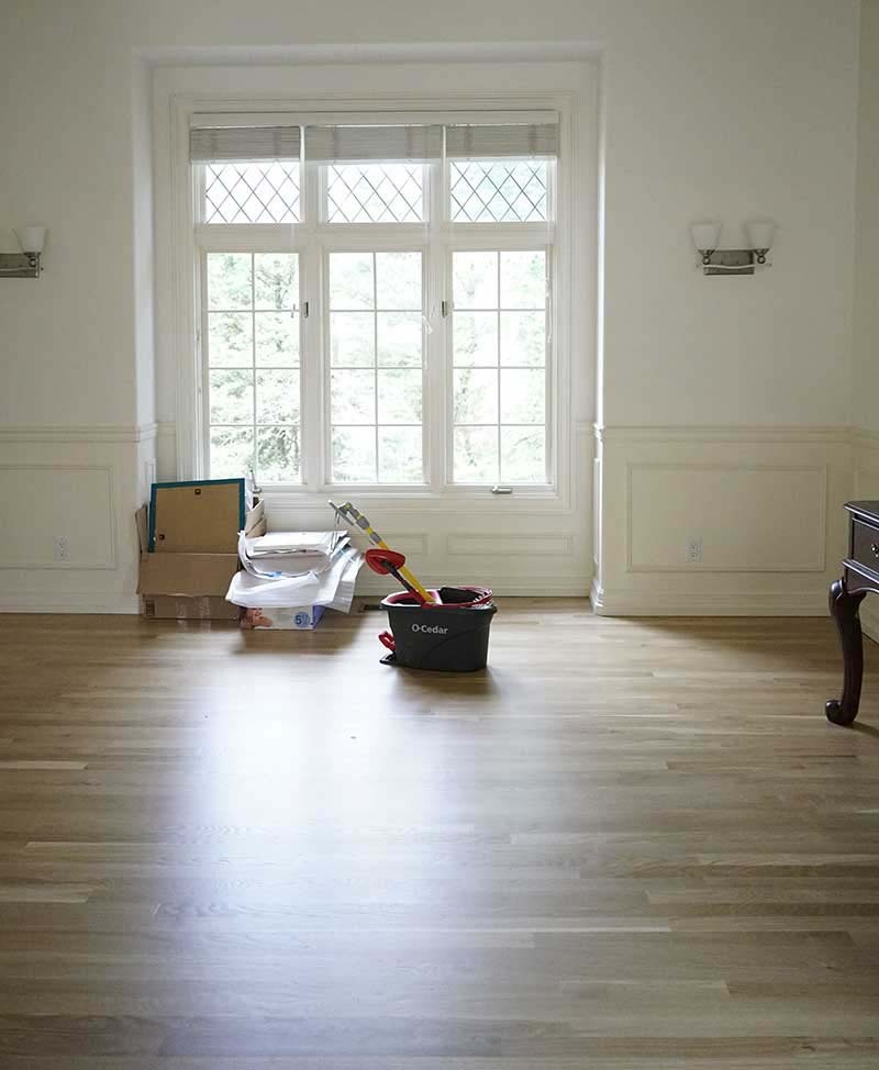 Move-in cleaning in progress in an empty Seattle home, mop and bucket on hardwood floors by Simply Clean